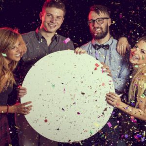 Group of friends having fun, celebrating New Year's Eve and holding a blank cardboard circle